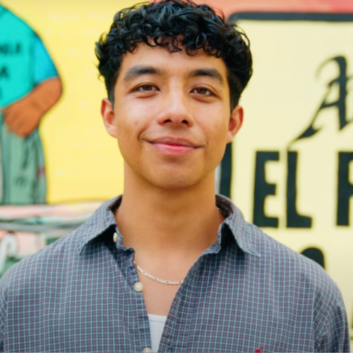 LMU student stands in front of a wall mural
